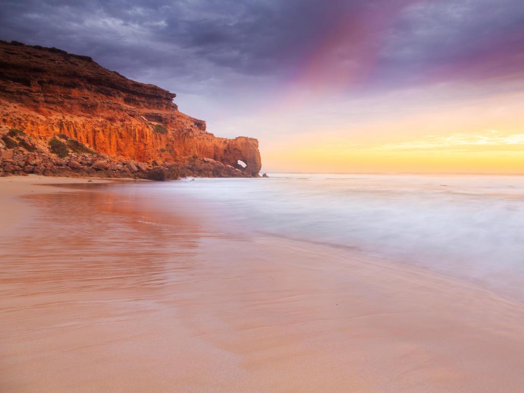 Venus Bay, Eyre Peninsula, South Australia with a stunning sunset at The Needle Eye at Venus Bay, sand and sea in the foreground and yellow cliffs in the distance. 