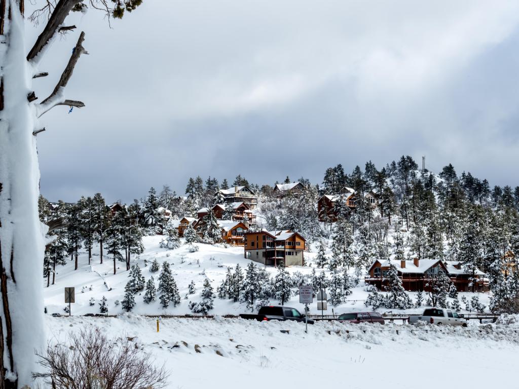 Bear Mountain ski resort, San Bernardino, Southern California, USA with a frozen lake in the foreground and snow covered trees and chalets in the distance.