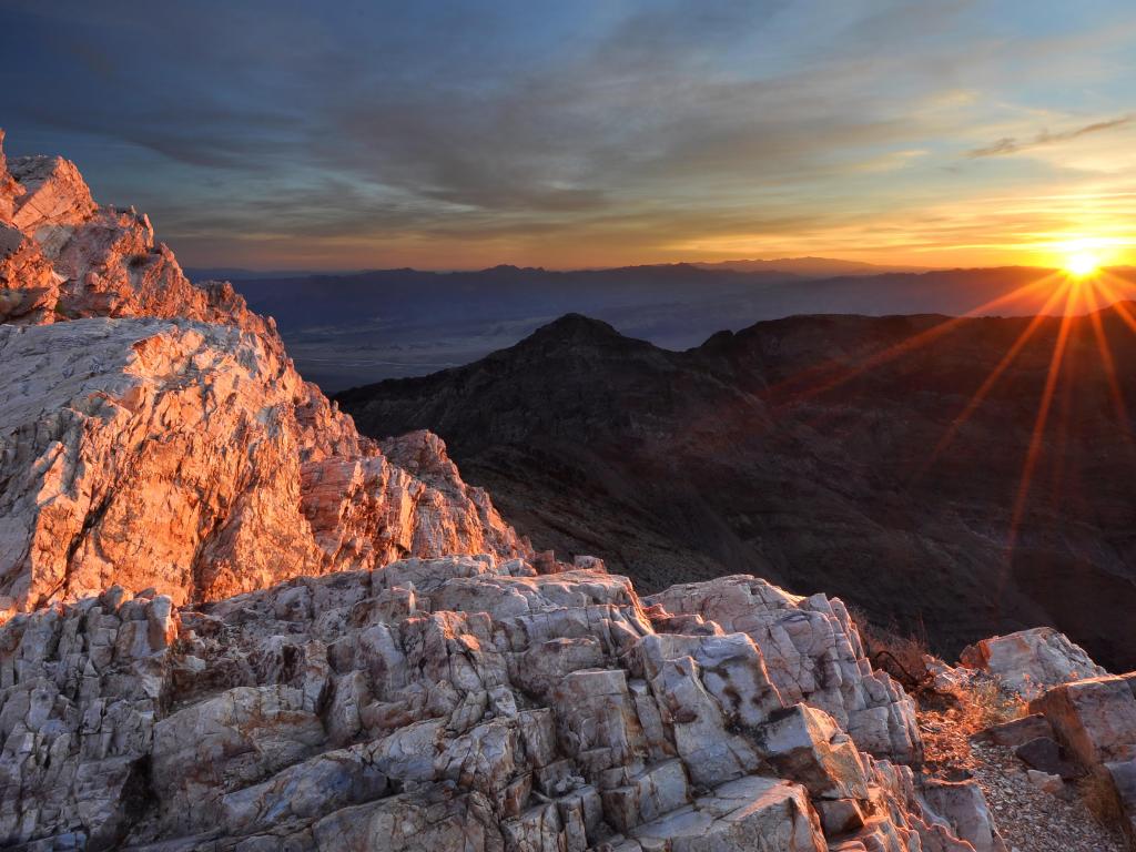 Death Valley National Park in the morning with mountains at the foreground and the sun rising in the background.