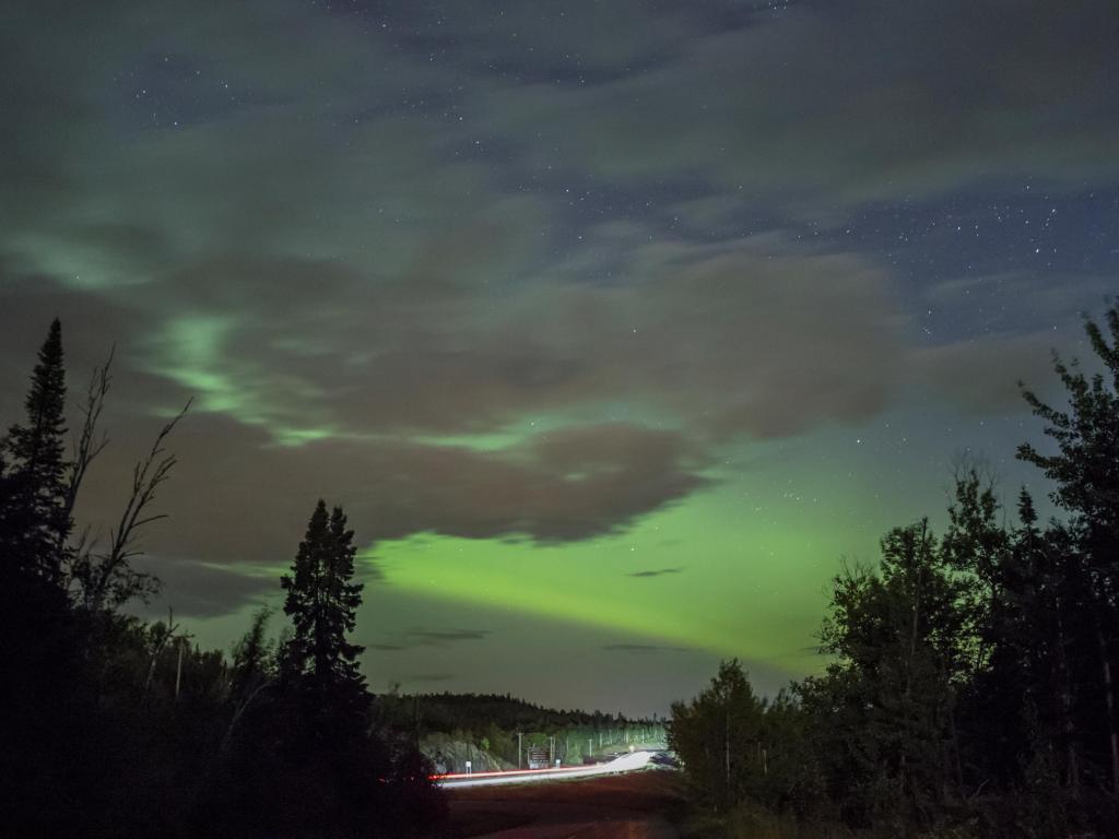 A Band of Green Northern Lights behind Partly Cloudy Night Skies above Traffic Trails on Highway 61 in Northern Minnesota