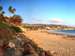 Golden Hour over the ocean, with wide sandy shoreline and empty beach at Main Beach in Laguna Beach