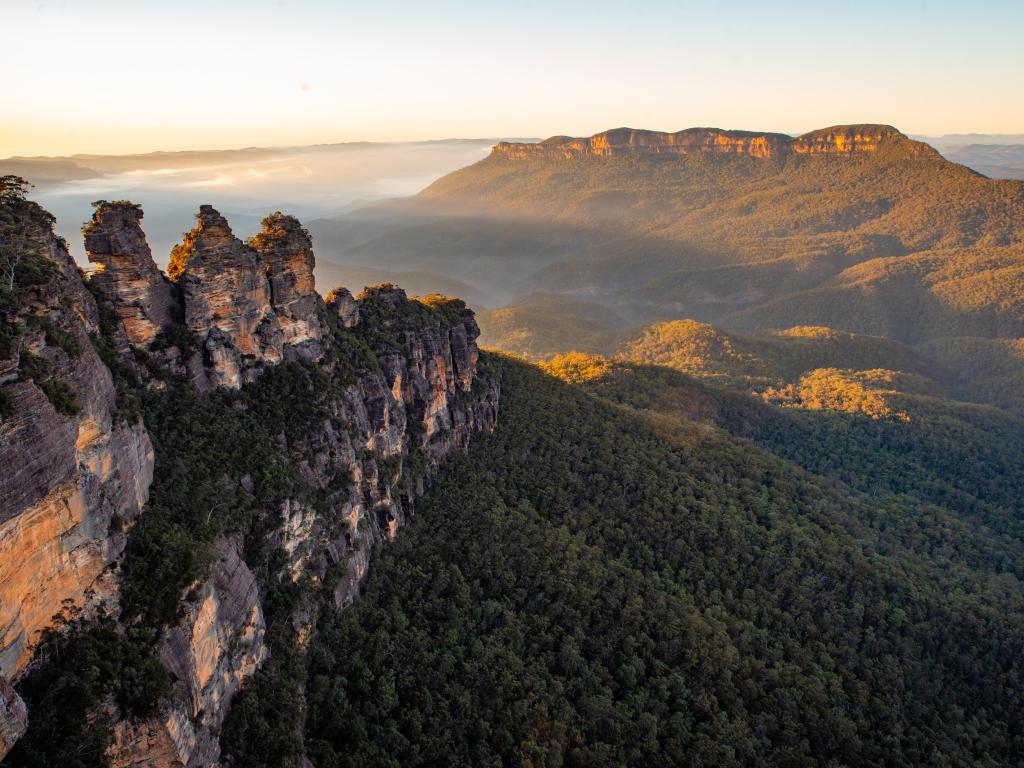 New South Wales, Australia with a panoramic sunrise at three sisters lookout over blue mountains valley with mist.