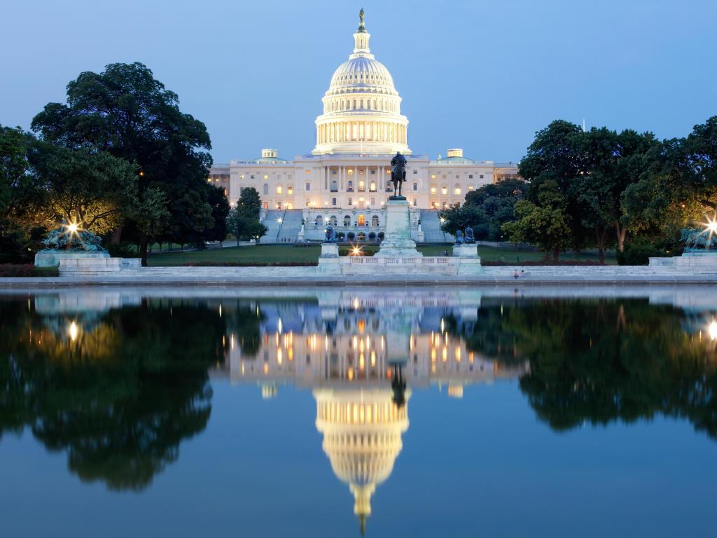 Washington DC, USA taken at the United States Capitol building after dark reflected in the water in the foreground.