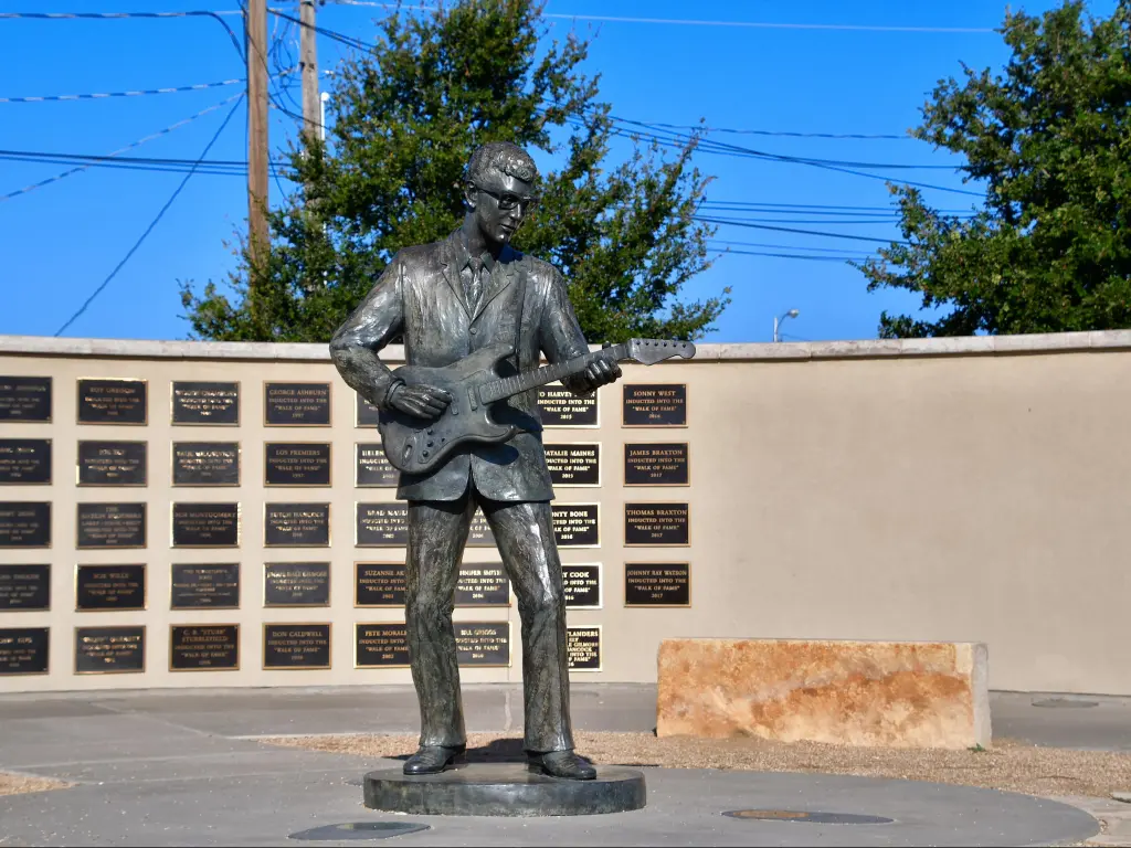 Buddy Holly Memorial in Lubbock on a sunny day with blue skies. The metal statue is dedicated to the rock and roll singer and artist.