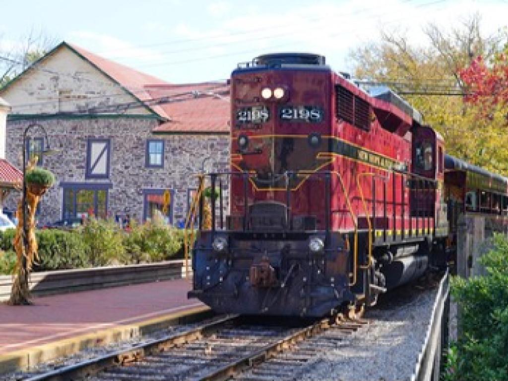 An old, dark red locomotive pulls into the station at the New Hope Railroad, PA