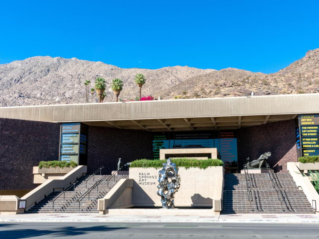 Exterior view of Palm Springs Art Museum on Museum Drive, steps leading to entrance and sculptures dotted around stairway