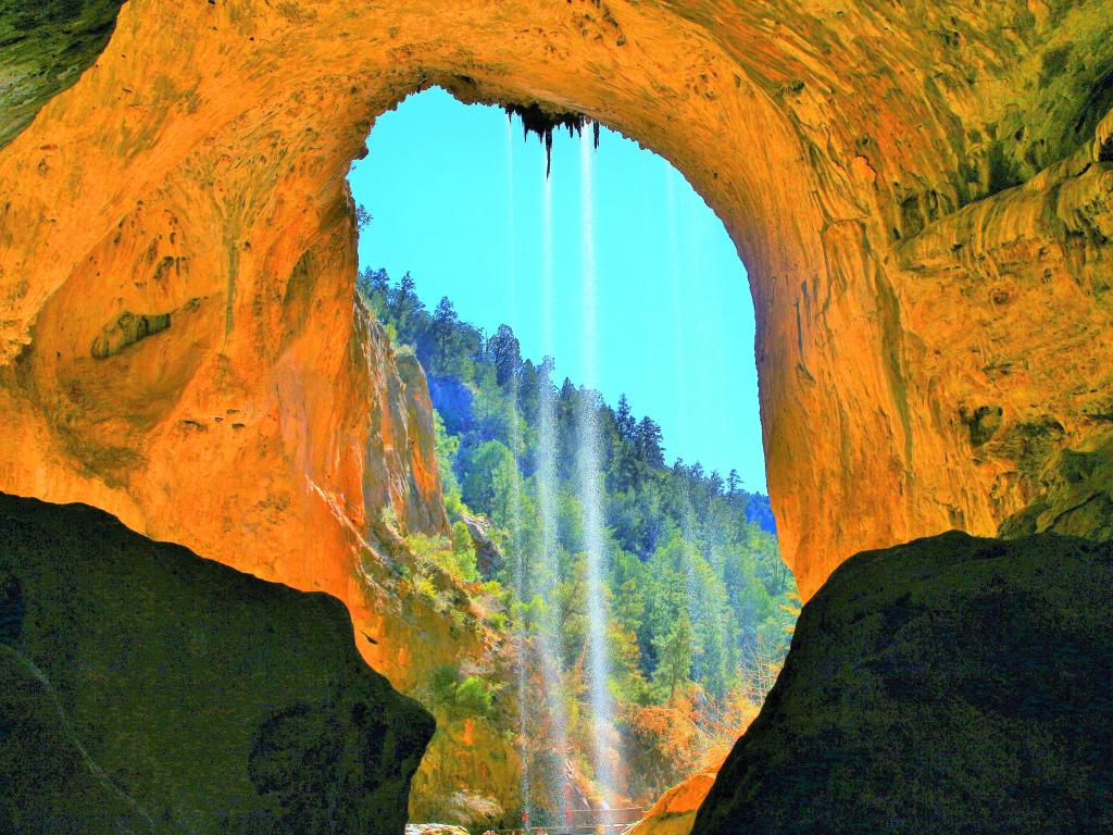 Tonto Natural Bridge, Arizona, in Tonto National Forest on a sunny day. Small streams of water run down from the arch.