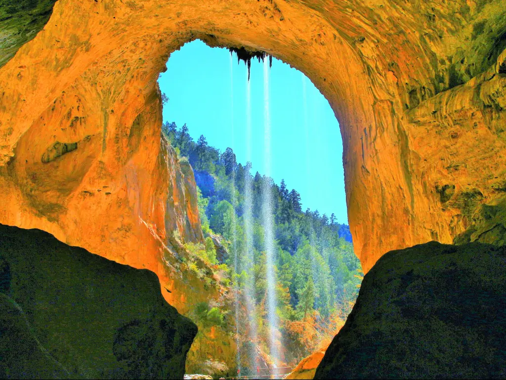 Tonto Natural Bridge, Arizona, in Tonto National Forest on a sunny day. Small streams of water run down from the arch.