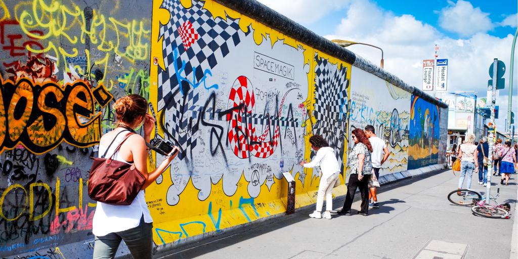 People look at the artwork painted onto the East Side Gallery section of the Berlin Wall