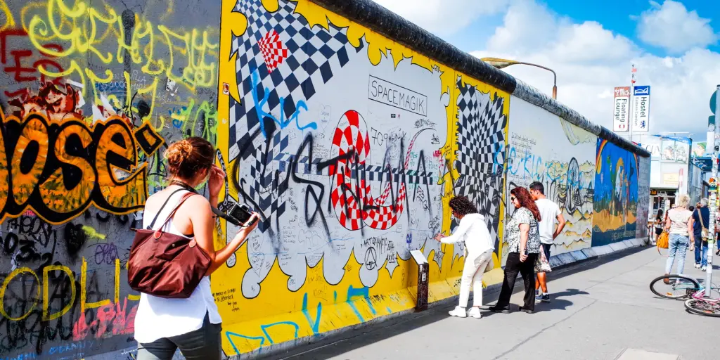 People look at the artwork painted onto the East Side Gallery section of the Berlin Wall