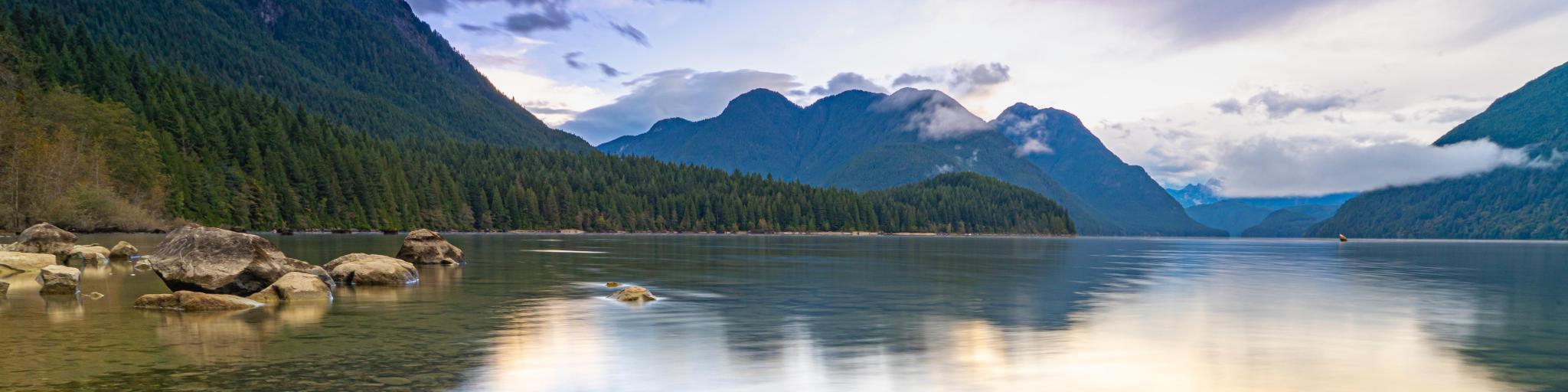 Golden Ears Provincial Park, BC, Canada with Alouette Lake in the foreground and the mountains in the distance reflecting in the calm water at sunrise. 