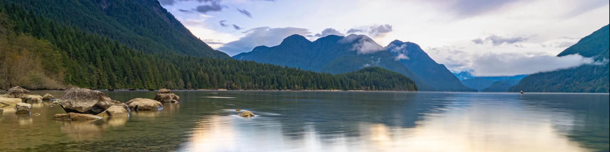 Golden Ears Provincial Park, BC, Canada with Alouette Lake in the foreground and the mountains in the distance reflecting in the calm water at sunrise. 