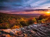Shenandoah National Park, Virginia at Autumn with a sunset in the distance, rocks in the foreground and overlooking the national park below.