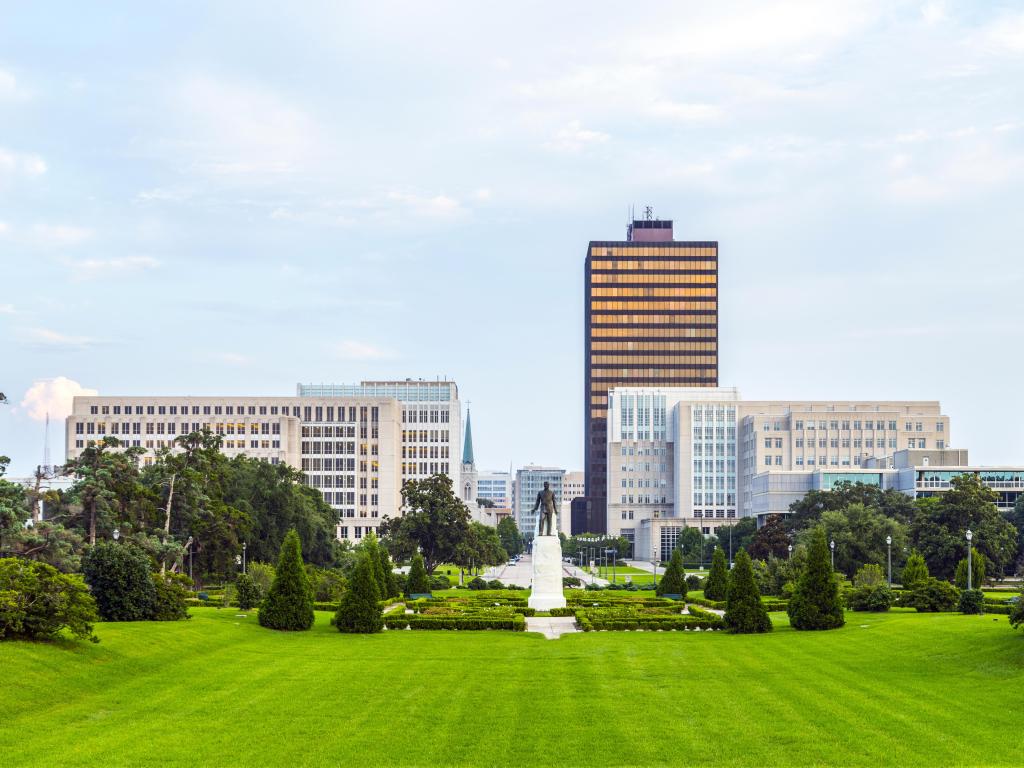 Baton Rouge, Louisiana, USA with the city skyline and Huey Long Statue in the distance, green park in the foreground taken on a sunny day.