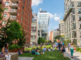 People relaxing in the sunshine at The High Line, New York, with skyscrapers in the background