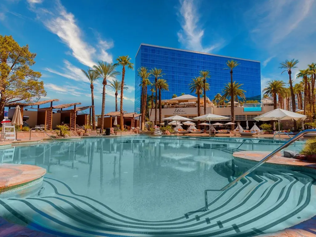 Poolside "beach" at Virgin Hotels Las Vegas surrounded by palm trees, sunny weather