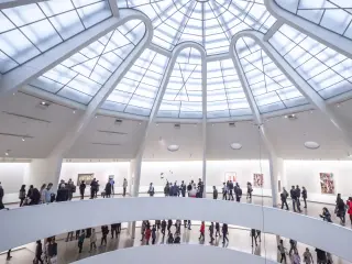 Busy interior of The Guggenheim Museum, with people walking between the gallery levels