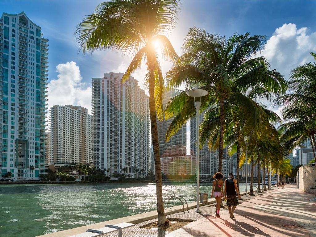 Walking path along Miami River in downtown Miami with the sun poking out from behind the clouds on a typical warm day.