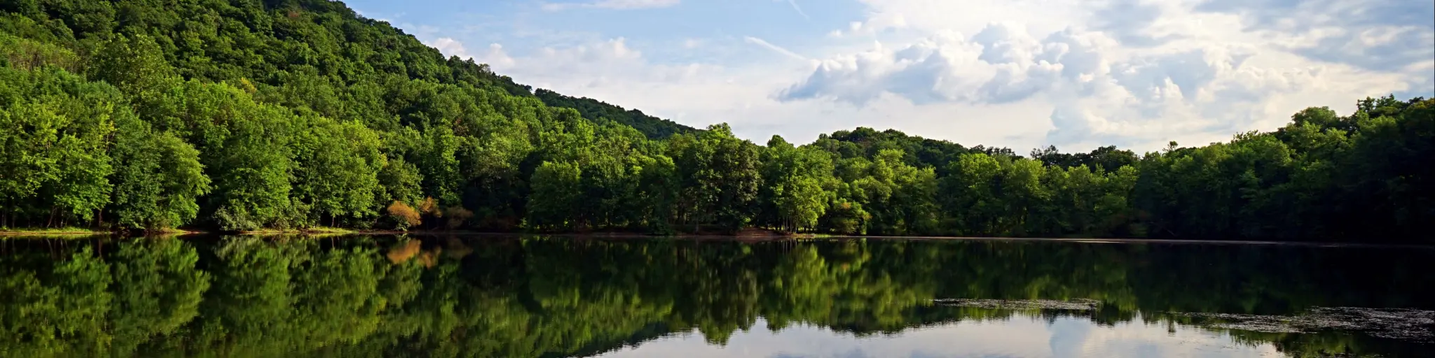 Mountains and clouds reflect in the still water of a lake at the Ramapo Valley County Reservation in Mahwah, New Jersey.