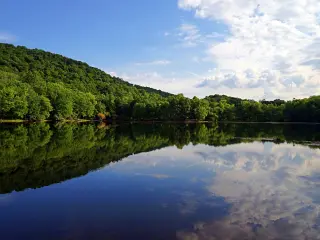 Mountains and clouds reflect in the still water of a lake at the Ramapo Valley County Reservation in Mahwah, New Jersey.