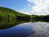 Mountains and clouds reflect in the still water of a lake at the Ramapo Valley County Reservation in Mahwah, New Jersey.