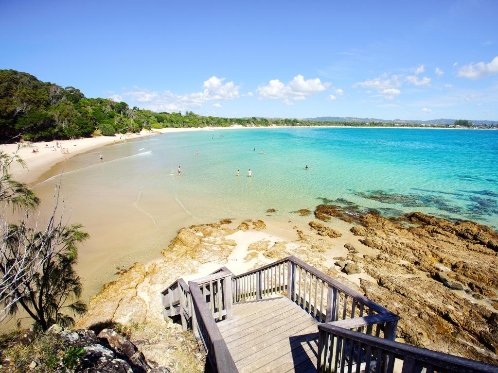 Wooden steps down to golden sand bay with turquoise water and green trees