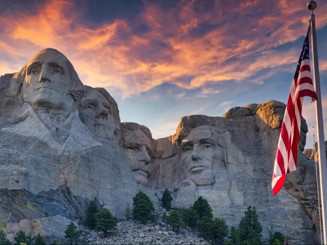 Mount Rushmore at sunset with US flag in the foreground