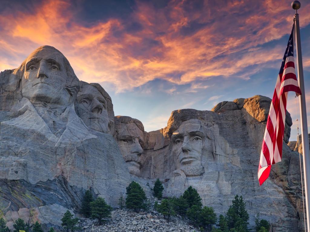 Mount Rushmore at sunset with US flag in the foreground