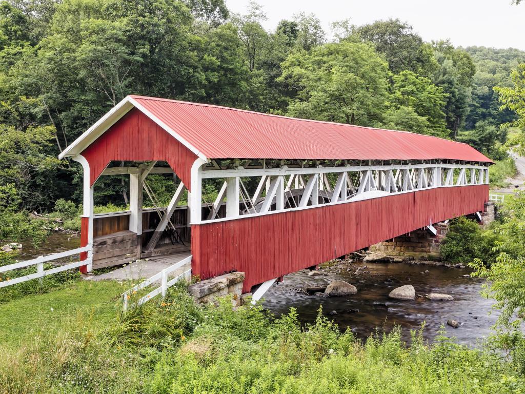 The historic red Barronvale Covered Bridge crossing Laurel Hill Creek on an overcast day