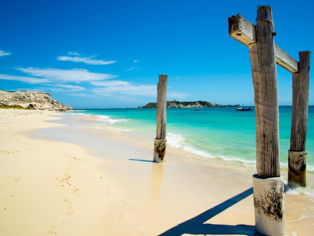 White sand beach with wooden structure in the foreground, turquoise sea and blue sky