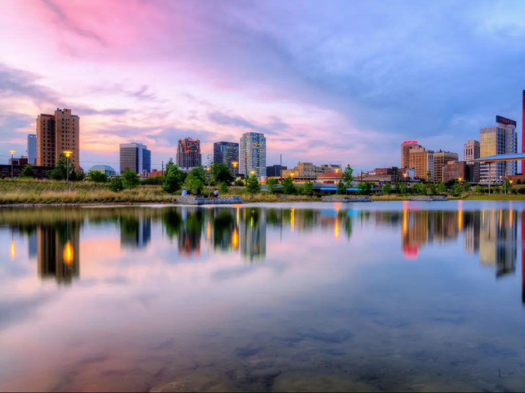 Birmingham, Alabama with calm water in the foreground reflecting the downtown skyline in the distance at sunset.