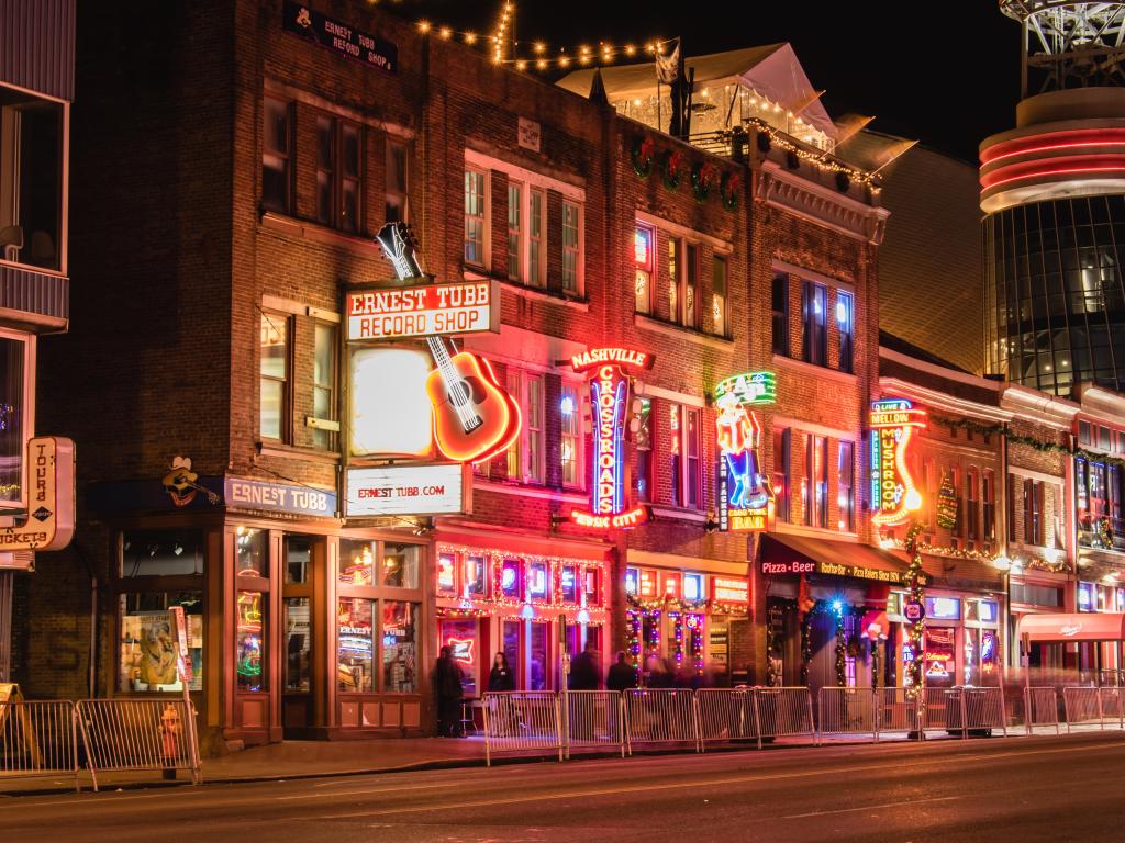 Nashville, Tennessee, USA with the iconic bars and venues line Broadway in downtown Nashville at night.