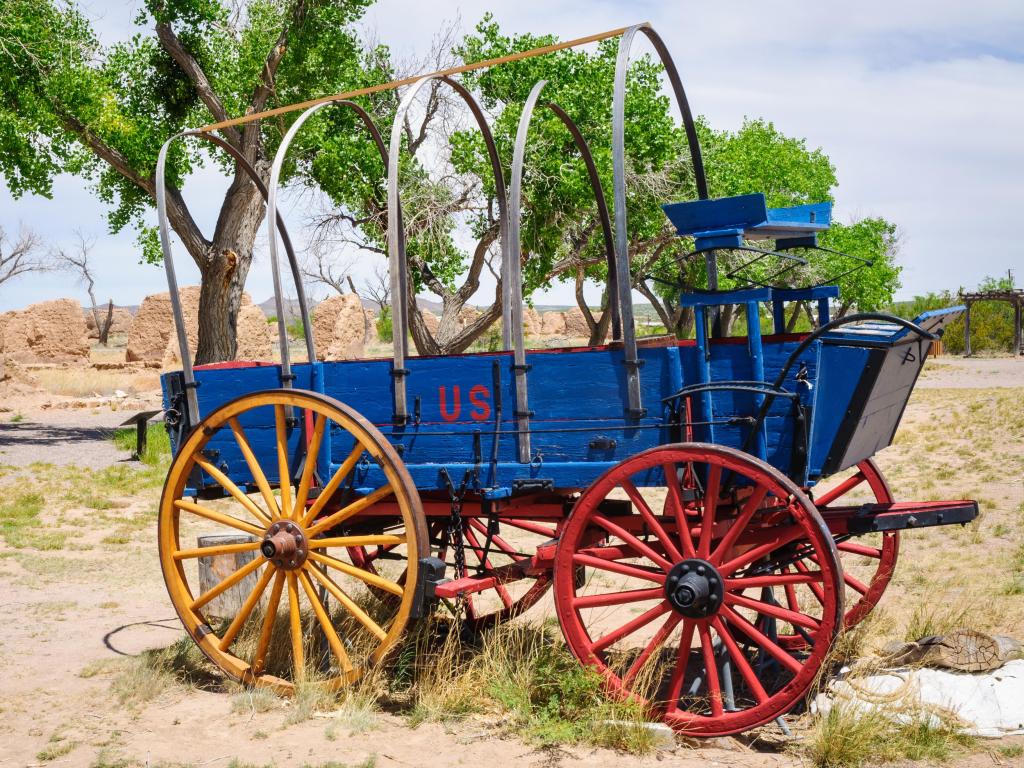Bright blue wagon with yellow and red wheels in the desert sands at Fort Selden State Monument