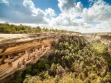 Homes built into steep rocky cliff, with deep tree lined canyon to the side