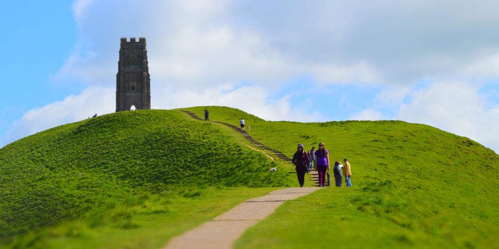 People walking down from Glastonbury Tor with the tower in the background 