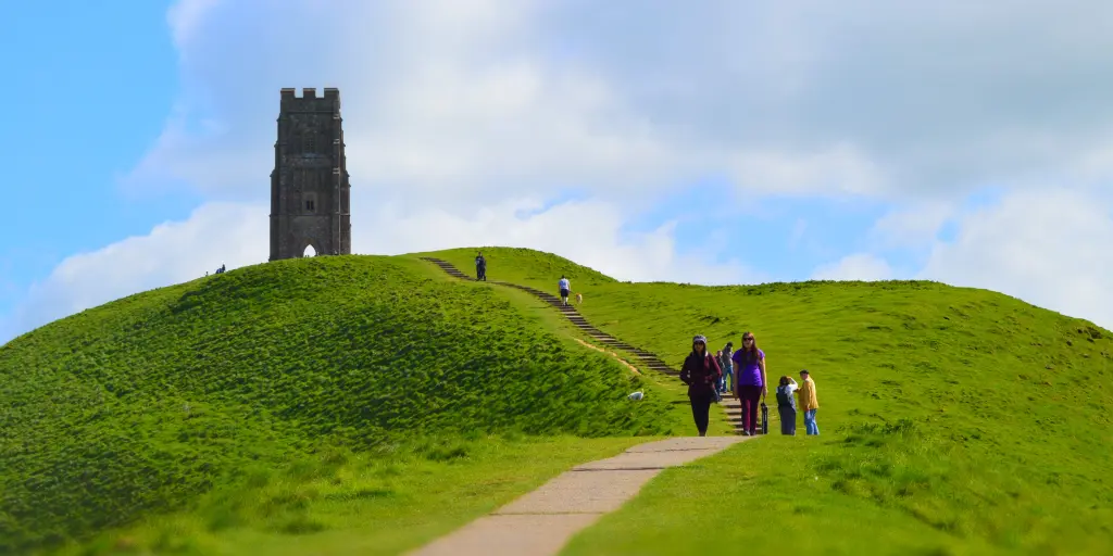 People walking down from Glastonbury Tor with the tower in the background 