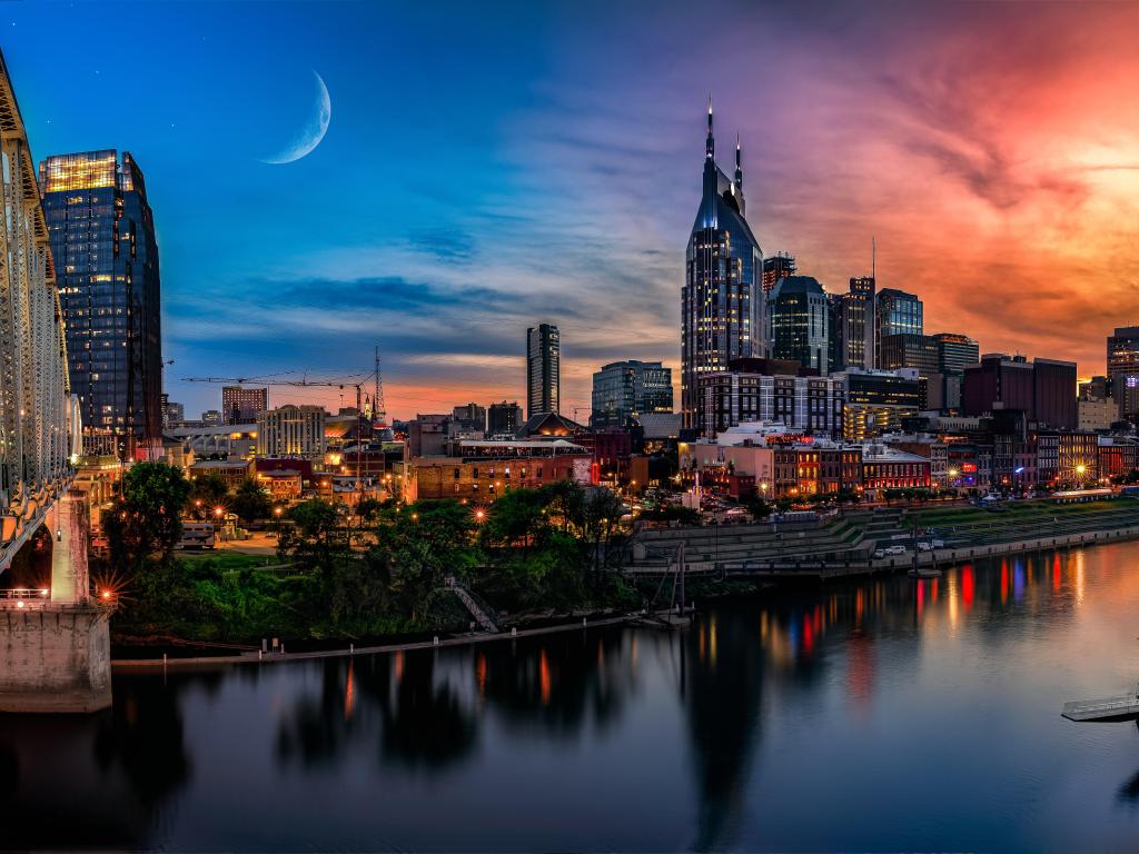 Nashville, USA taken at sunset with a dramatic sky, the city skyline in the distance and the river in the foreground. 