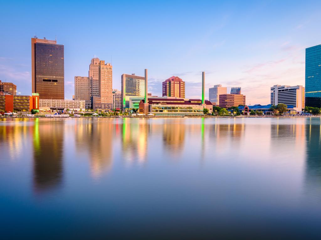 Toledo, Ohio, USA with the downtown skyline on the Maumee River at dusk reflecting in the water in the foreground.