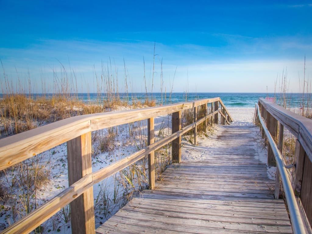 Pensacola Beach, Florida, USA with the white sandy beach and boardwalk, sea in the distance on a sunny clear day.