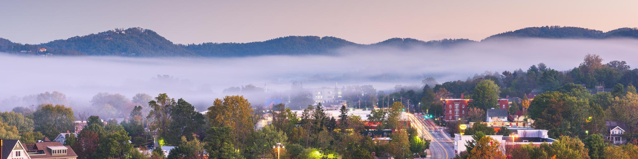 Asheville, North Carolina, downtown skyline at dusk with mountains and fog in the background