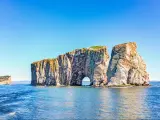 Perce Rock, Gaspe Peninsula, Quebec, Canada with the sea in the foreground and the cliff formation in the background on a clear sunny day.