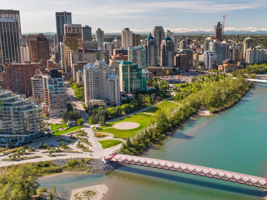 Calgary, Alberta, Canada with Peace Bridge over Bow River and the city downtown skyline in the distance on a sunny day.