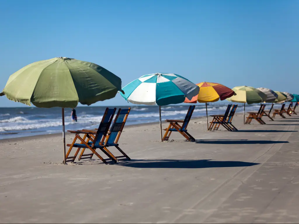 Sun chairs and colorful sun umbrellas on the beach in Galveston, Texas.