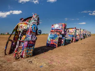 Cadillac Ranch in Amarillo, a popular landmark on historic Route 66, on a sunny day. There are several Cadillac cars in the sand, upside down.