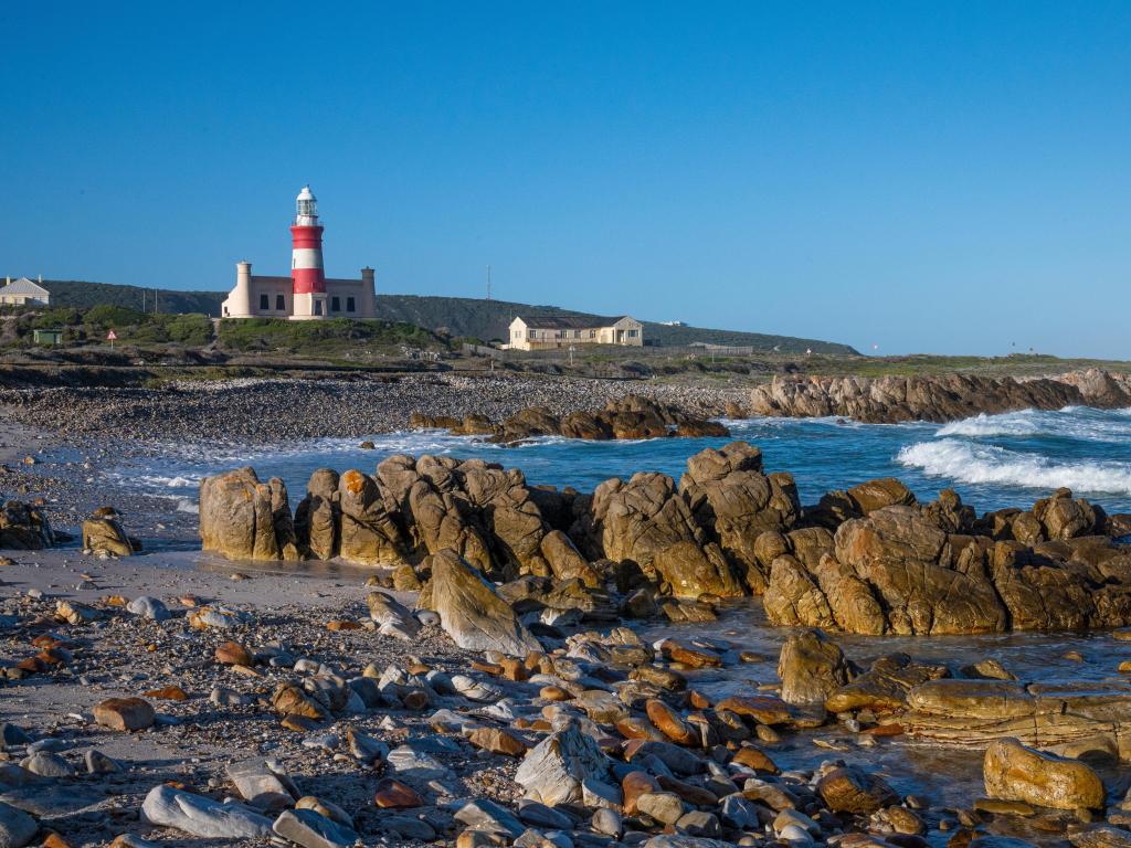 Famous lighthouse seen in the distance, with standing rocks on the shore in focus