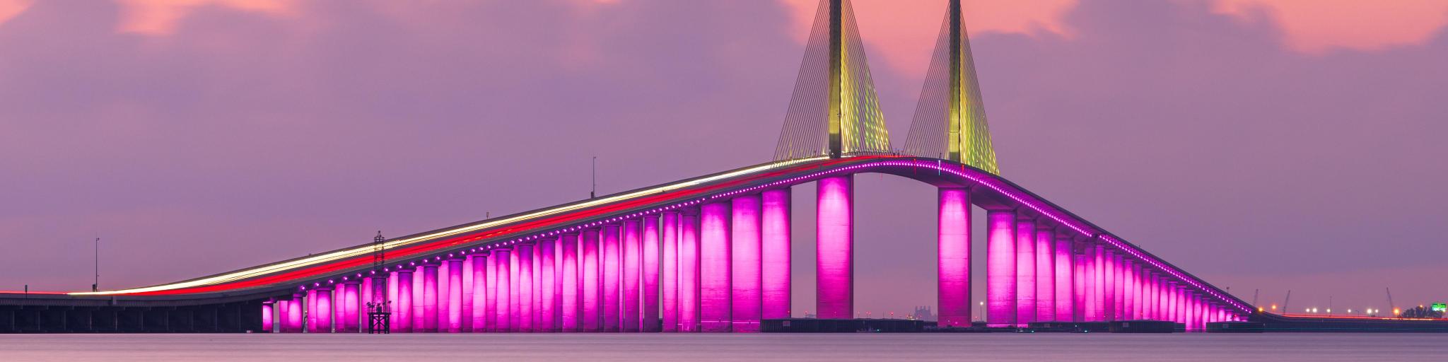 Sunshine Skyway Bridge, St. Petersburg spanning the Lower Tampa Bay at sunset and lit up in a bright pink.