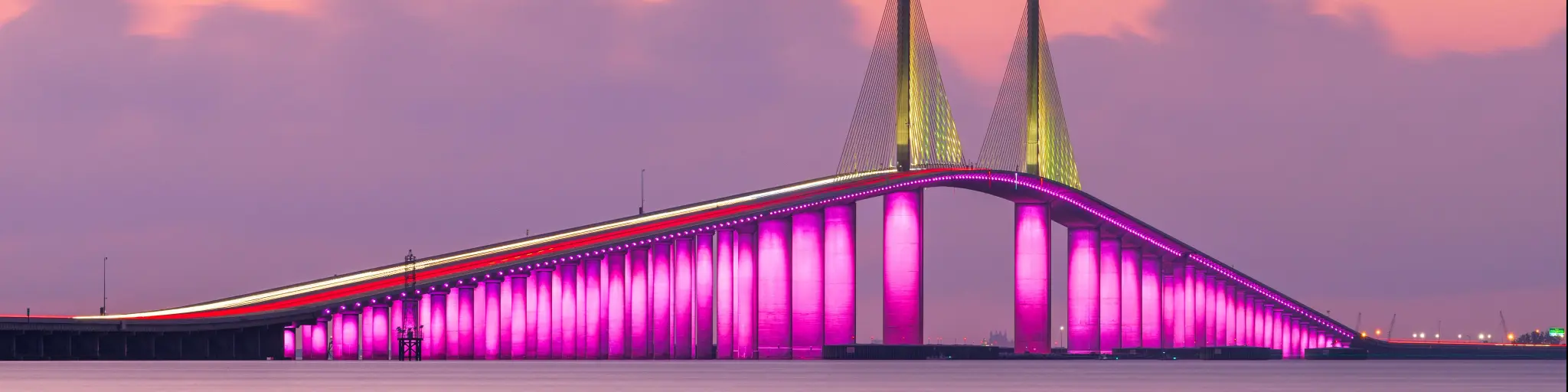 Sunshine Skyway Bridge, St. Petersburg spanning the Lower Tampa Bay at sunset and lit up in a bright pink.