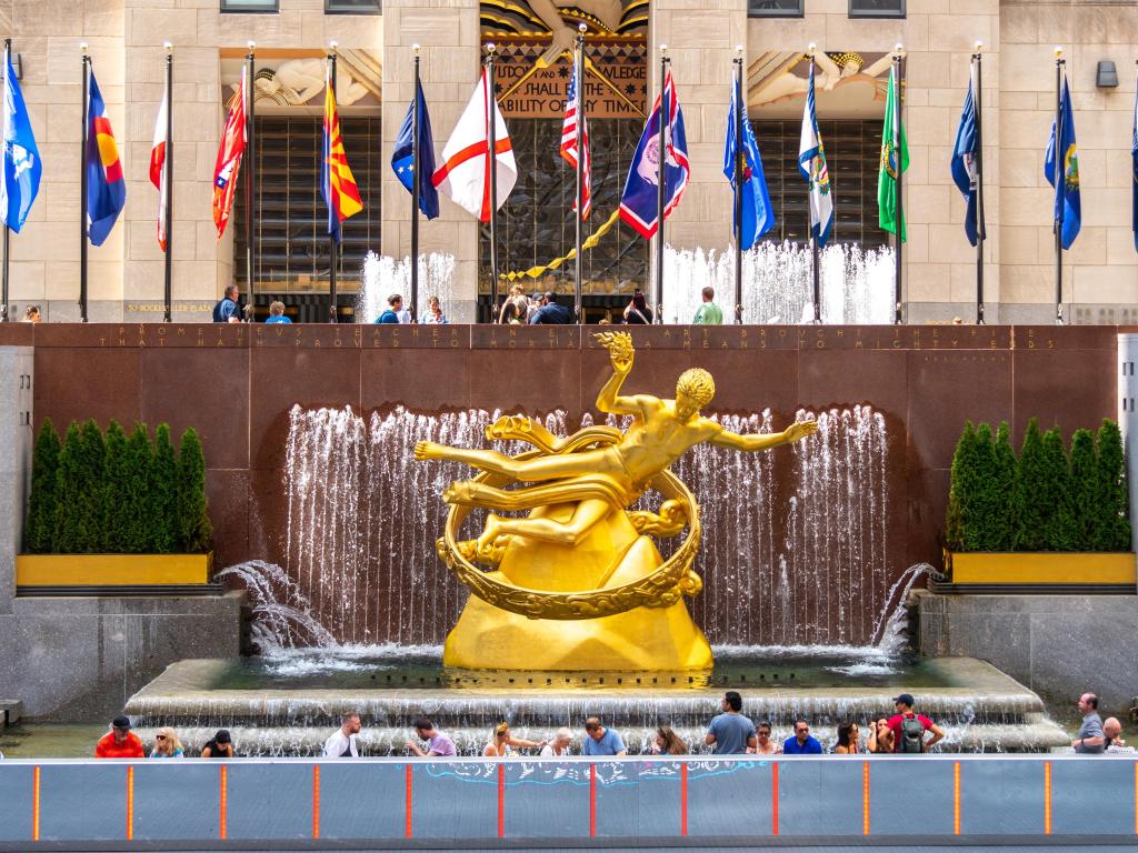 Rockefeller Square with fountain and gold statue of Prometheus, surrounded by different country flags