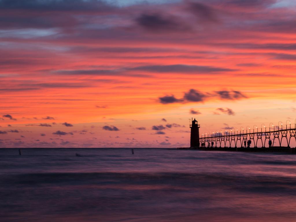 Historic lighthouse shown in silhouette against a vivid sky at sunset