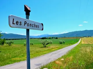 A road sign in France with a road in the background and lots of very green countryside